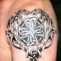 Tatuaje en el hombro de cruz céltica con dos bestias