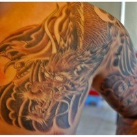 Dragone con la sfera tatuato sulla spalla