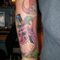 tatuaje en el brazo de amplio payaso morado sonriendo con calavera