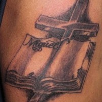 el tatuaje conmemorativo de una cruz con un libro y el nombre escrito en el hecho en color negro