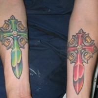 Red and green cross tattoos on both arms