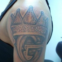 Krone mit Monogramm Tattoo an der Schulter