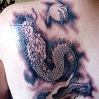 drago con la luna piena in artiglio tatuaggio