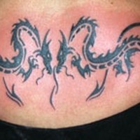 Le tatouage de deux dragons tribaux sur le bas du dos