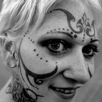 Tattoo von Schnörkeln und Pünktchen auf dem Gesicht