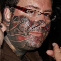 Tatuajes en parte inferior del rostro de color gris y rojo
