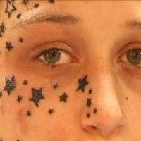 Muchas pequeñas estrellas tatuados en un parte de la cara