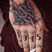 Tatuaje en el mano y en los nudillos, ojo con alas, fecha, signos