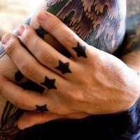 Tattoo von vier kleinen schwarzen Sternen an Fingerknöcheln
