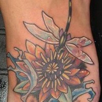 Le tatouage coloré de libellule avec une fleur sur le pied