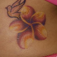 Une fleur orange en style artistique avec le tatouage d'un oiseau en vol sur la hanche