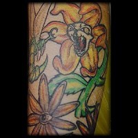 Le tatouage d'une fleur en coller  qui attaque une abeille sur le bras