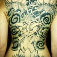 Le tatouage de tout le dos avec un lotus impressionnant dans le ciel noir