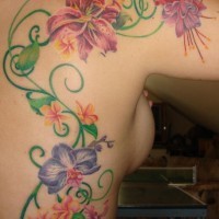 Tatuaje en color la vid con las flores brillantes en la espalda y el hombro
