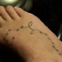 Feines Tattoo von Faden mit Blättern auf dem Fuß