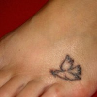 Tattoo von kleiner nichtfarbiger Taube mit einem Blatt auf dem Fuß