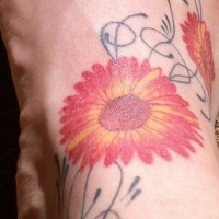 Tattoo von rotgelben Blumen auf dem Fuß