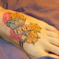 Un diamant et des fleurs avec le tatouage de mot la maman sur le pied