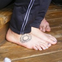 Tattoo von runder nichtfarbiger Blume auf dem Fuß