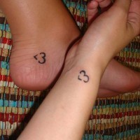 Kleine nichtfarbige herzförmige Tattooes auf Hand und Fuß