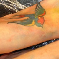 Tattoo von bunter fliegender Schwelbe auf dem Fuß