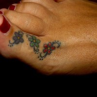 Tatuaje en el dedo pulgar del pie, tres flores diminutas