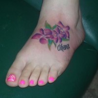 Tattoo von drei lila Blumen und weiblichem Namen auf dem Fuß