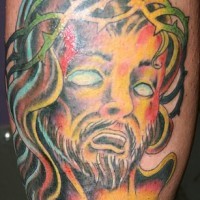 Parti-coloured jesus in despair, forearm tattoo
