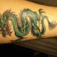 Tatuaje en el antebrazo, diseño de color radiante verde, dragón con orejas largas