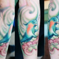 Tatuaje en el antebrazo, pajarito brillante  con alas desplegadas, sentado en la rama