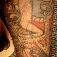Tattoo von strengem nacktem Mann, der eine Schlange hält, am Unterarm