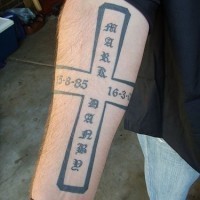 Tatuaje en el antebrazo, cruz tridimensionales con fechas y jeroglíficos escritos en ella