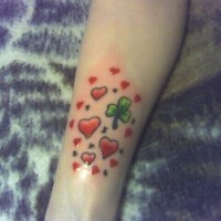 Many red hearts and patrick's leaf forearm tattoo