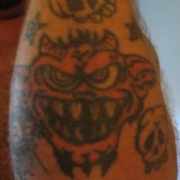 Tatuaje en el antebrazo, demonio rojo que se ríe, cráneo