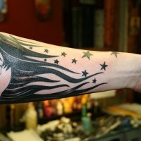 Mezzo viso della donna con i capelli lungi e le  stelle tatuati sul braccio