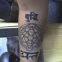 Disegno in forma rotonda  e la scritta in lingua straniera tatuati sul braccio