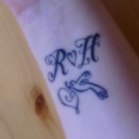 Tatuaje de iniciales, un corazón y un pajaro