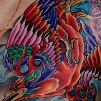 el tatuaje muy colorado de la ave fenix volando hecho en el pecho