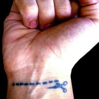 Tattoo von gestrichelter Linie und Schere am Handgelenk