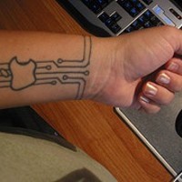 Apple logo on digital board arm tattoo