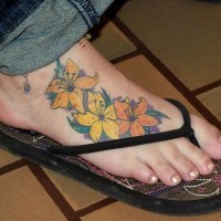 Le tatouage des fleurs jaunes et oranges sur le pied