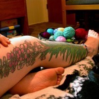 Large plant with pink flower tattoo on whole leg