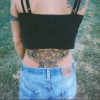 tatuaje grande femenino en la base de la cola de tracería