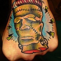 Tattoo von missmutigem grünem als Roboter, gestaltetem Kopf an der Hand