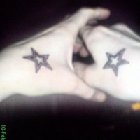 Tatuaje en la mano, dos estrellas con contornos negros y rojos