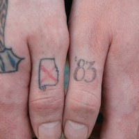 Tattoo von kleinem Zeichen und Zahl an Daumen