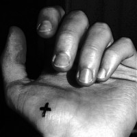 Tattoo von winzigem fettbedrucktem Kreuz in Schwarz an der Hand