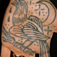 Tatuaje en la mano, graznidos de cuervo en el cielo nocturno