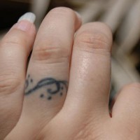 Tattoo von kleinem stilisirtem G-Schlüssel mit Pünktchen  an dem Finger