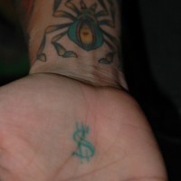 Tattoo von großer farbiger Spinne und Dollarzeichen  an der Hand